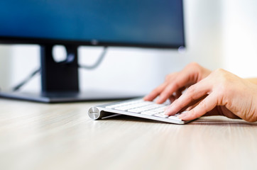 Closeup of female hands on the white wireless keyboard
