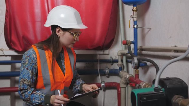 Woman engineer checks the meter readings in the boiler room.