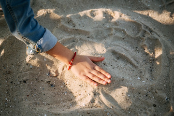 child in a denim jacket playing with shells on the sand of the beach