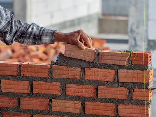 Bricklayer worker installing brick masonry on interior wall