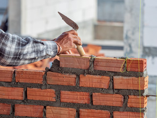 worker using trowel and tools for building interior walls with bricks and mortar