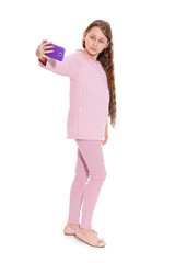 A girl of 10-11 years old in a pink suit takes a selfie from a smartphone. Isolation on a white background.