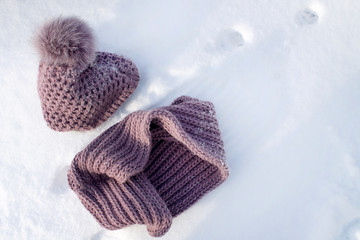 Winter hat with a scarf are on the white snow. The concept of the arrival or departure of winter.