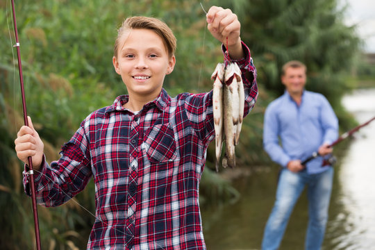 Portrait of glad boy having fish in hands
