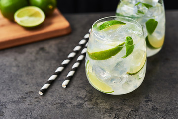 Lemonade or mojito with lime, mint and ice on dark concrete table. Summer drink. Copy space for text. Selective focus.