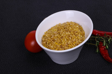 Raw bulgur in the bowl with tomatoes and garlic