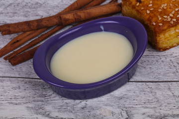 Condenced milk in the bowl with sinnamon and pastry