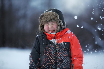 incredible emotions of a little boy playing with snow in winter. Boy shows tongue