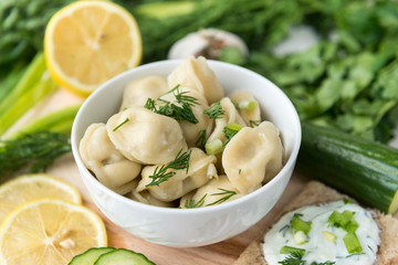 plate with dumplings with greens, greens, cucumber, lemon