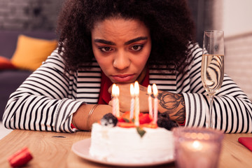 Cheerless unhappy woman looking at the candles