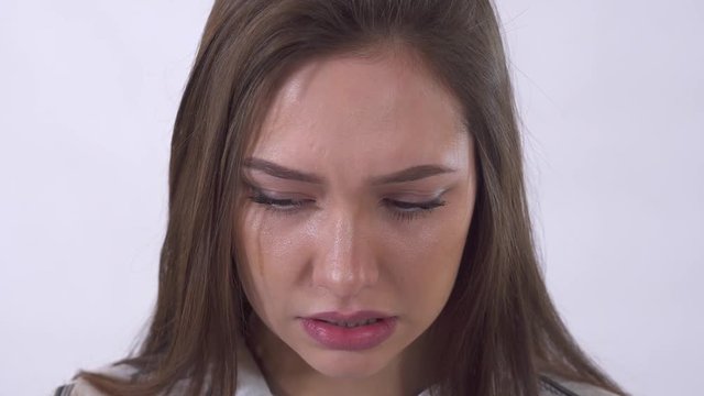 Close up portrait of young crying woman with tears. Shooting in the studio on a white background