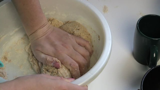 Woman kneads dough in a basin. Utensils and tools for baking bread. Cooking bread at home...