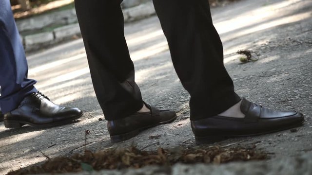 a young man businessman is waiting in the summer on the street. Feet large, slow motion video