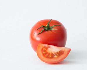 A whole red tomato and a slice