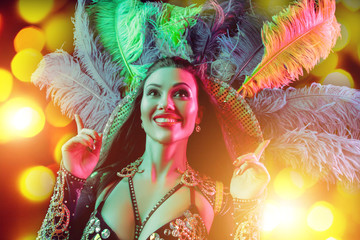 Beautiful young woman in carnival peacock costume. Beauty model woman at party over holiday background with magic glow. Christmas and New Year celebration. Glamour lady with perfect make up and © master1305