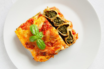 stuffed with beef and spinach cannelloni in tomato and bechamell sauce and decorated with basil leafs