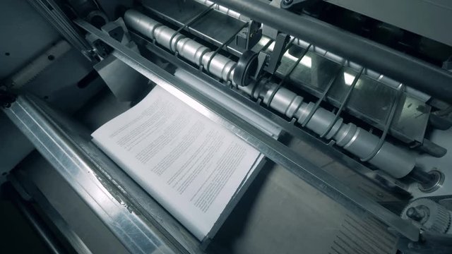 Top view of printed pages getting released by the factory machine