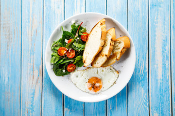Breakfast - fried egg, toasts and vegetable salad