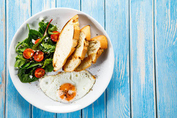 Breakfast - fried egg, toasts and vegetable salad