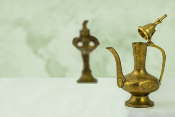 Fototapeta na wymiar Arabian brass ware. A bright table top with a old brass arabic teapot in front of abstract blurred background. Space for montage.