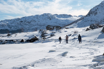 Fototapeta na wymiar Tourists group walking on snow hill at sunny