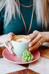 The girl is holding a Cup of cappuccino coffee. Hands close up.