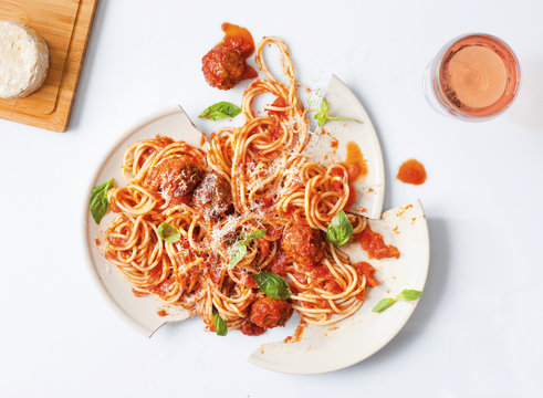 dropped plate of spaghetti and meatballs with wine and cheese