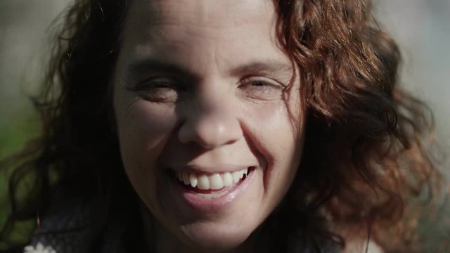 Close up shot of smiling mature woman looking at camera. Attractive elderly woman with curly hair during sunne day. Mature beauty concept