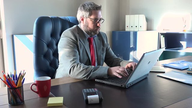 Tired director snorting bored and working non stop. Annoyed caucasian manager typing on keyboard, stressed chief writing on computer dullness. Busy man at office, no break time, stressful lifestyle