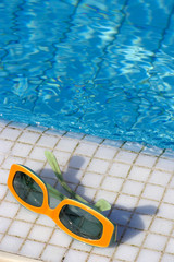 Sonnenbrille liegt am Poolrand