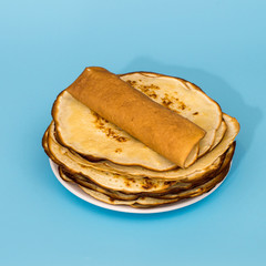   Traditional homemade thin pancakes on blue background with copy space. Russian kitchen. 