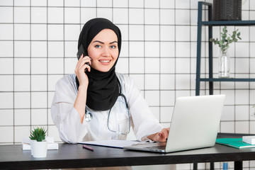 Muslim female doctor writing report on her working desk