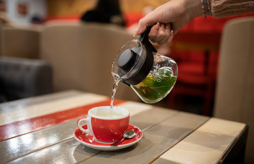 Female hand pours tea into a cup