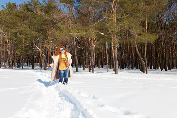 Fototapeta na wymiar Full length of happy pretty woman going through snowy forest