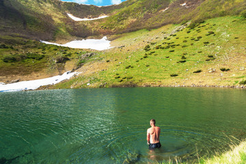 Tourists have a rest and bathing in the mountains on the mountainous lake in the Ukrainian Carpathians.