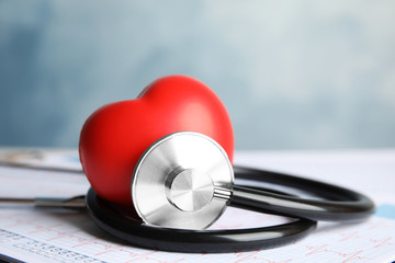 Stethoscope, red heart and cardiogram on table. Cardiology concept