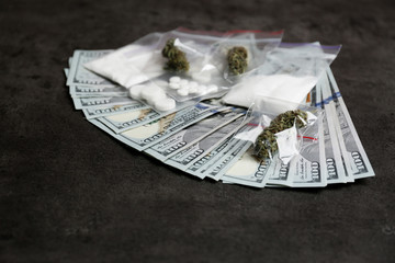 Plastic bags with cocaine, pills, hemp buds and money on grey background