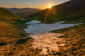 The lake in the Ukrainian Carpathians in the summer season in the high mountains with snow.