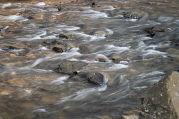 Water flowing around the rocks in a creek. Low shutter speed.
