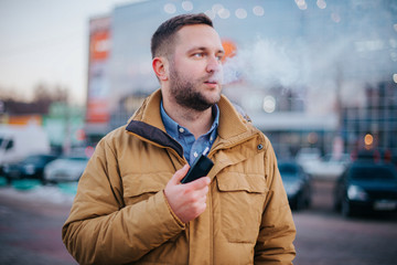 Modern young man with a beard fun smoking Electronic Cigarette