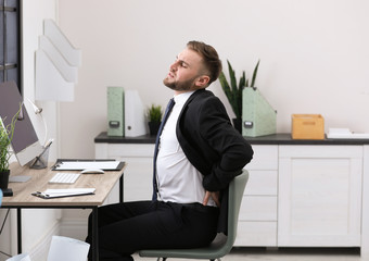Businessman suffering from back pain at workplace