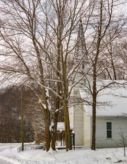 winter white country church with steeple in the snow