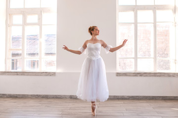 Young graceful ballerina dancing on white studio.