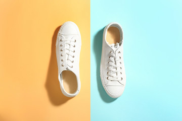 Pair of stylish sneakers on color background, top view
