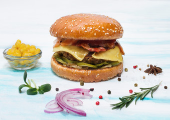 Juicy beef burger with cheese, cucumbers, bacon on a white background. Side view