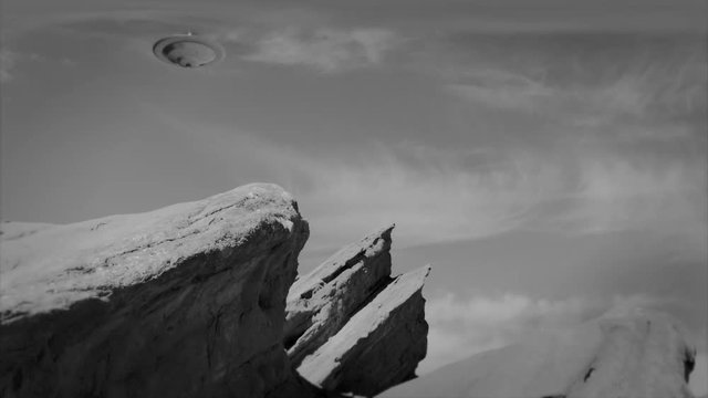 ALIEN SPACESHIP HOVERS ABOVE A DESERT LANDSCAPE.  8mm FILM EFFECT IN 4K, 10 BIT BLACK AND WHITE.