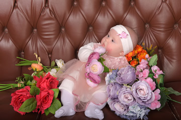 girl five months in a pink dress with bouquets of flowers