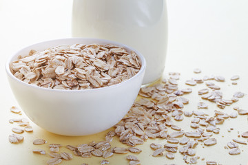 bottle of milk and oat flakes in a bowl, vegetarian or vegan food, healthy breakfast