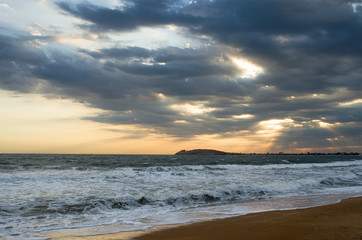Fototapeta na wymiar Evening on the beach, the waves wash the sandy beach, the sunset sky picturesque clouds on the horizon, the far coast.