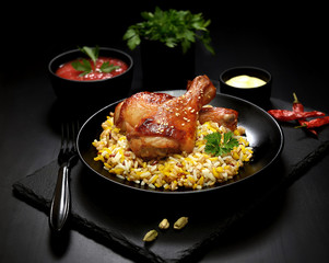 grilled chicken legs with sesame and rice on a black background